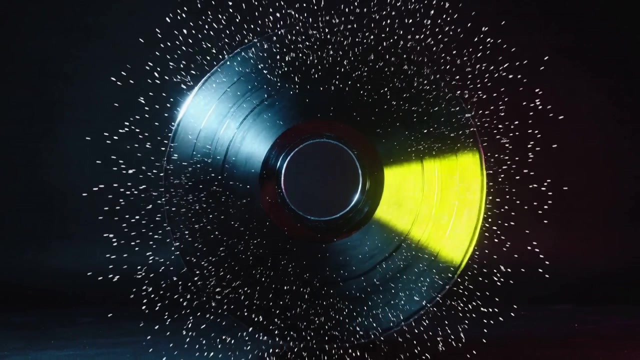 En roterende vinylplade rammes af en lysstråle, udsender partikler og fanger kantlys i et studie.