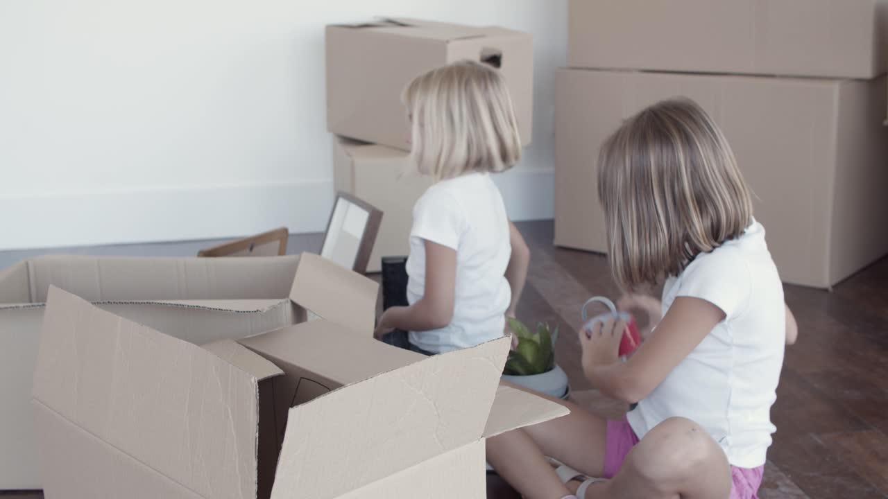 Adorable girls unpacking things in new apartment