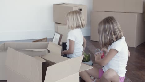 adorable girls unpacking things in new apartment