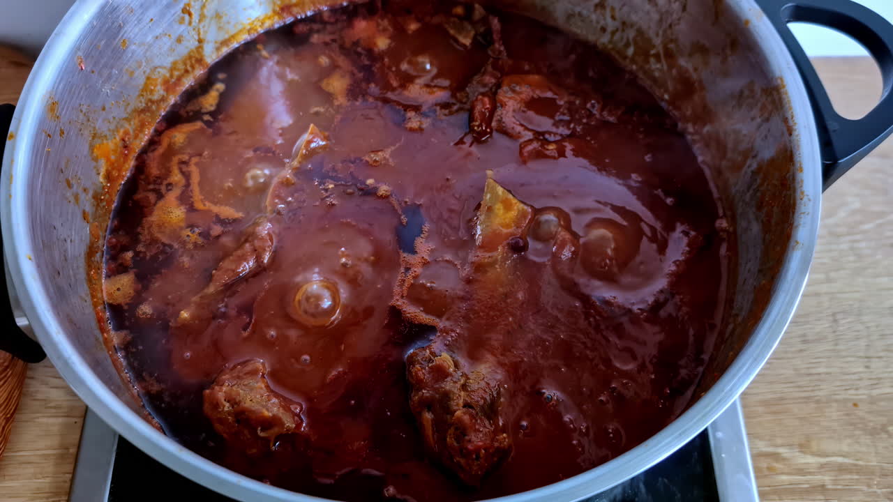 Closeup view featuring chicken pieces in sauce on oven getting cooked for guests in Jelgava, Latvia.