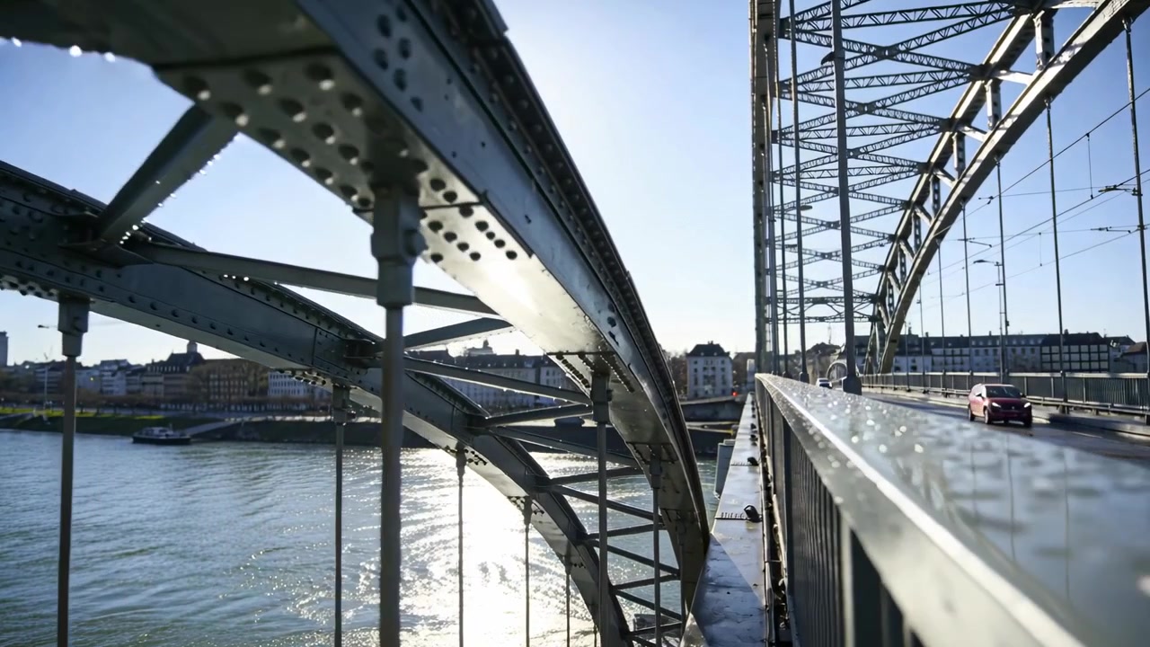 Moving camera along walkway, revealing curved steel arch and wet handrail, capturing sun reflection