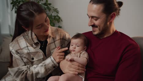 Nahaufnahme-Einer-Glücklichen-Mutter-In-Einem-Karierten-Hemd,-Die-Mit-Ihrer-Kleinen-Tochter-Spielt,-Während-Sie-Von-Ihrem-Vater-In-Einer-Modernen-Wohnung-Gehalten-Wird.-Glückliche-Eltern,-Die-Mit-Ihrer-Tochter-In-Einer-Modernen-Wohnung-Spielen