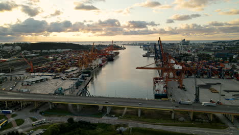 aerial shot showing industrial harbor of gdynia with cranes for freight and driving cars on bridge over river