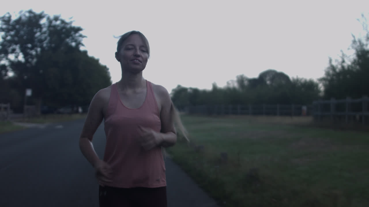 primer plano de una mujer joven corriendo en un camino del parque en un hermoso entorno verde
