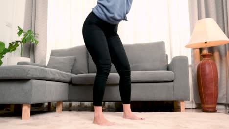 a woman squat in the living room of your house. exercise at home.