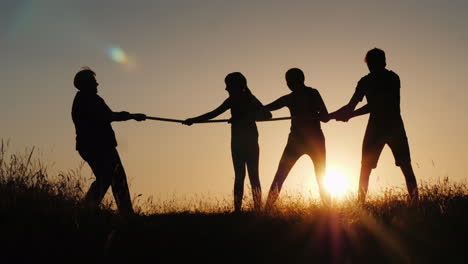 a strong older woman is competing with young people in tug-of-war active elderly people