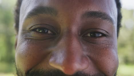 Porträt-Eines-Glücklichen-Afroamerikanischen-Mannes,-Der-Im-Park-In-Die-Kamera-Blickt,-Zeitlupe