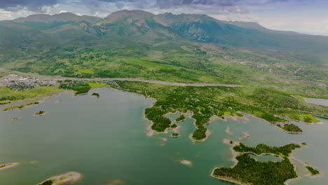 beautiful river with little grassy islands at the foot of stunning mountains of colorado, usa. drone footage over the amazing landscape on cloudy day.