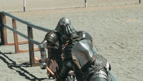 Group of knights fighting with weapons. One knight falling down. Knock out. Summer medival festival.