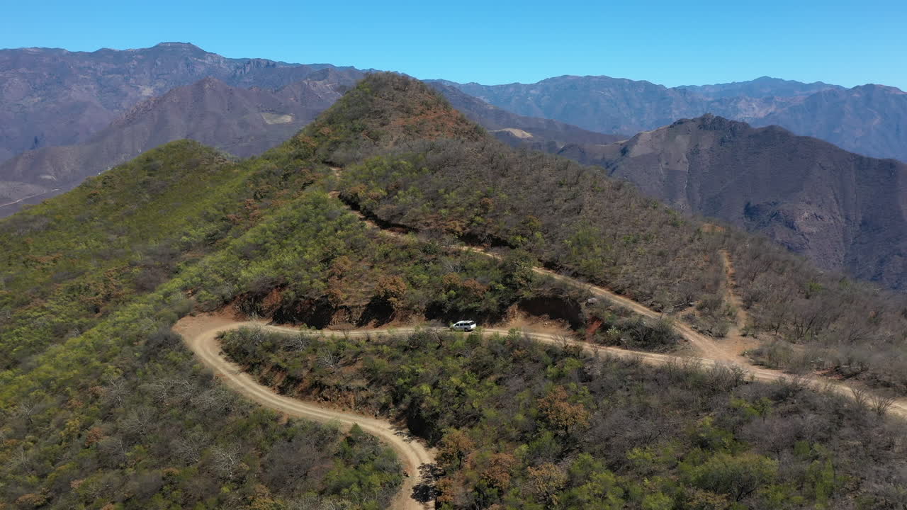 비포장 도로에서 내리막을 운전하는 흰색 자동차, 후방 공중