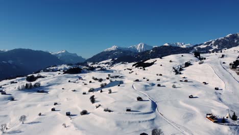 Rural-mountain-landscape-during-winter-with-snow-and-wooden-cabins