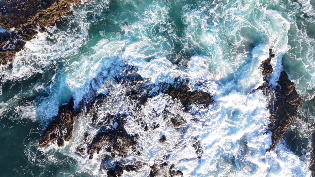 Ripresa cinematografica di onde che si infrangono sugli scogli dell'oceano. Lenta salita da appena sopra gli scogli fino al cielo.