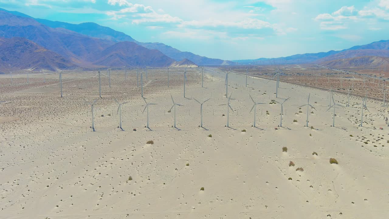 toma aérea de un parque eólico en el desierto de palm springs | montañas en el fondo | iluminación de la tarde