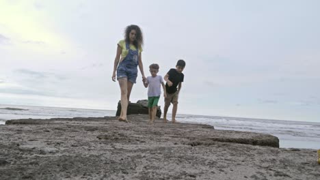 madre e hijos caminando descalzos por la playa