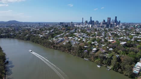 boat cruising on brisbane river with distant view of city skyline in queensland, australia