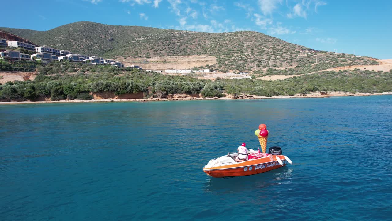 Drone of small boat selling ice cream in shallow crystal blue waters on the Turkish Riviera in Bodrum