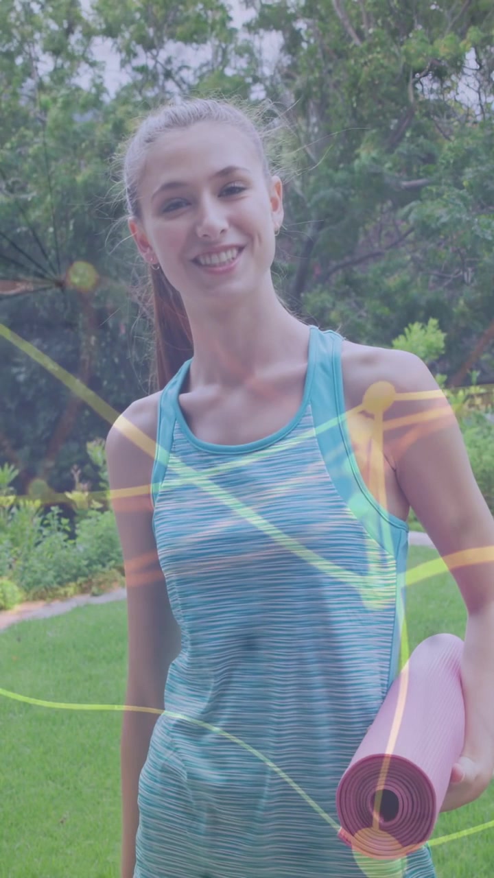 Video verticale: Donna che si prepara per l'allenamento, muovendosi e sorridendo mentre tiene un tappetino rosa, con delle strisce che passano.