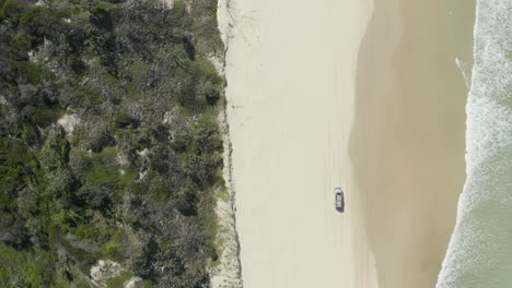 4K-Drohnenaufnahme-Eines-Autos,-Das-An-Einem-Weißen-Strand-Fährt