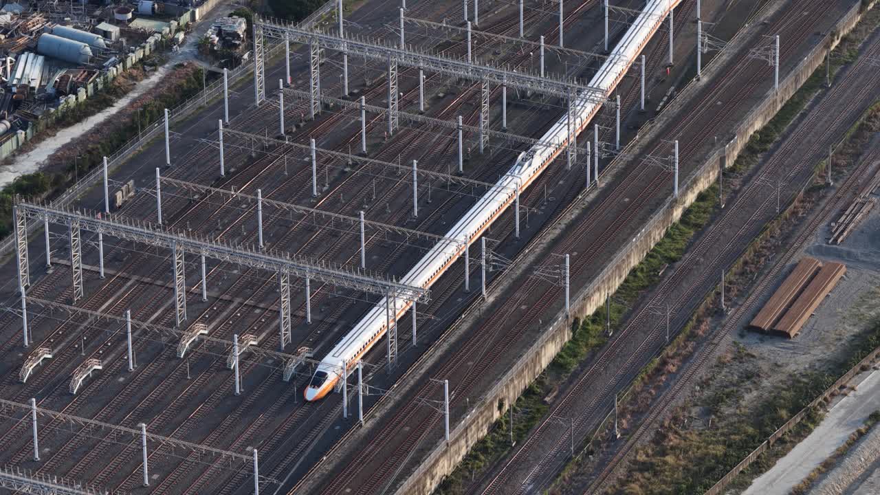 Aerial high angle perspective of a modern white bullet train moving swiftly on a complex railway junction, showcasing advanced public transportation infrastructure and efficient travel technology