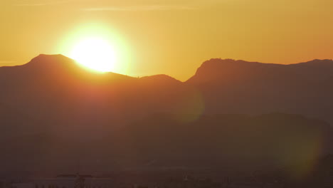 Ein-Leuchtend-Orangefarbener-Sonnenuntergang-In-Den-Bergen