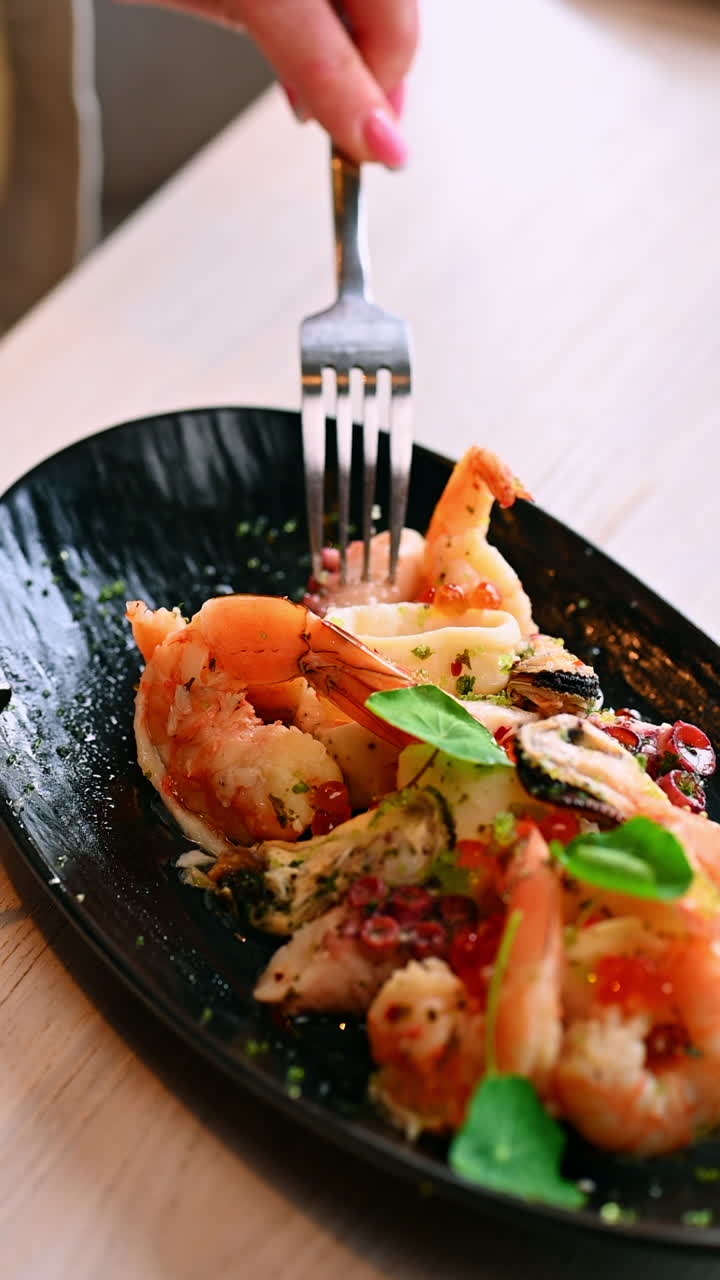 Close up of seafood salad on plate. Macro of shrimp and octopus seafood salad with herbs and sauce in restaurant setting