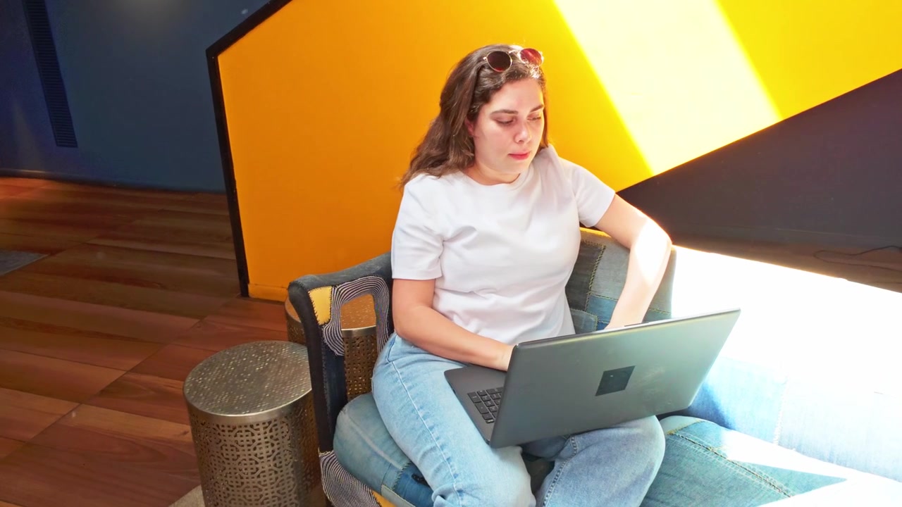 Donna che lavora da remoto con il laptop in una lobby confortevole