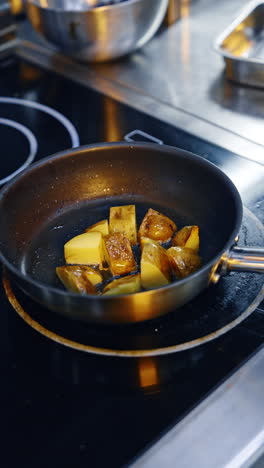 pieces of potatoes in a peel are fried in the oil in frying pan. cooking side dish on the stove. close up. vertical video.