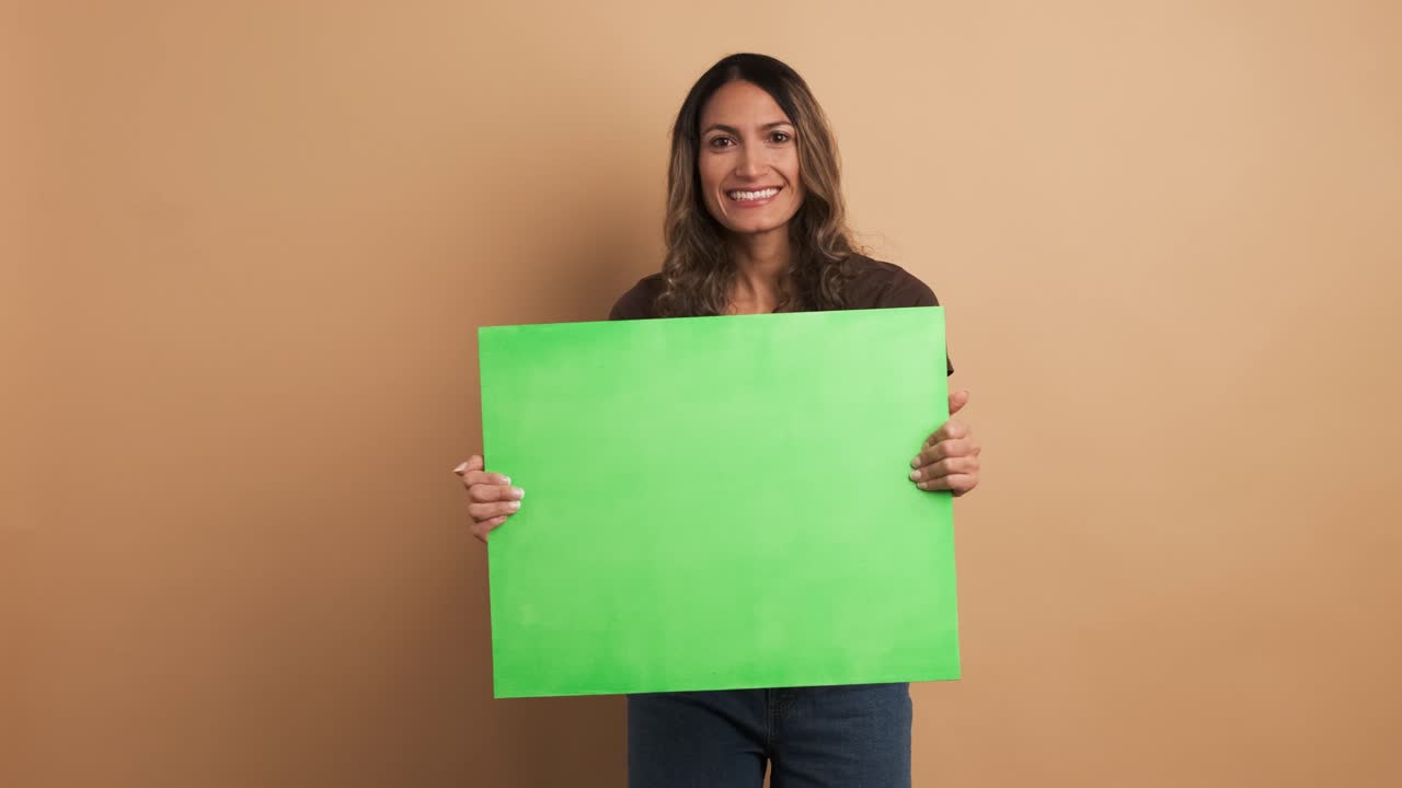 Smiling woman holding a green banner and gesturing thumb up