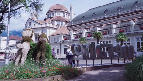 La-Gente-Camina-Por-El-Paseo-Del-Balneario-Mientras-Otros-Se-Toman-Fotografías-Y-Selfies-En-El-Centro-De-La-Ciudad-De-Meran,-Cerca-Del-Kurhaus.