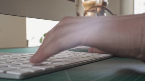 professional creative working at his desk in home office studio typing on keyboard and using wireless mouse close up 4k