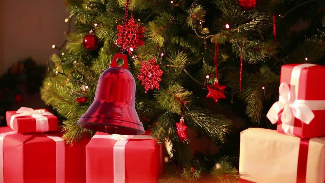 Animation of christmas bell bauble decorations over christmas tree with gifts