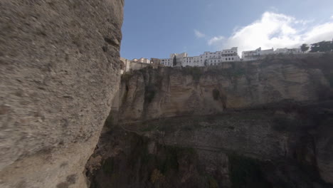 Unique-aerial-rounds-steep-cliff-to-reveal-arch-bridge-over-deep-gorge