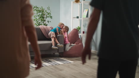 mother and father join hands focus on boy kissing sister