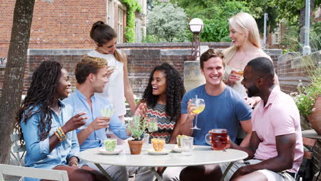 portrait of friends meeting for drinks at outdoor tables in restaurant