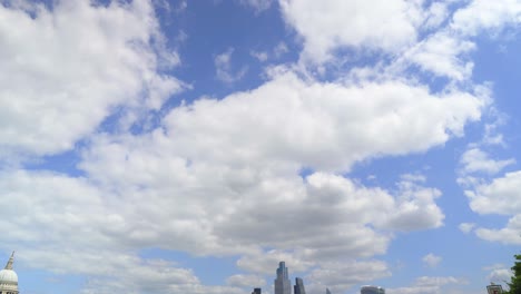 standing by the thames river london canary wharf big buildings in the background looking up to the sky and slowly moving down to reveal the city view on a sunny day with clouds cinematic scenery