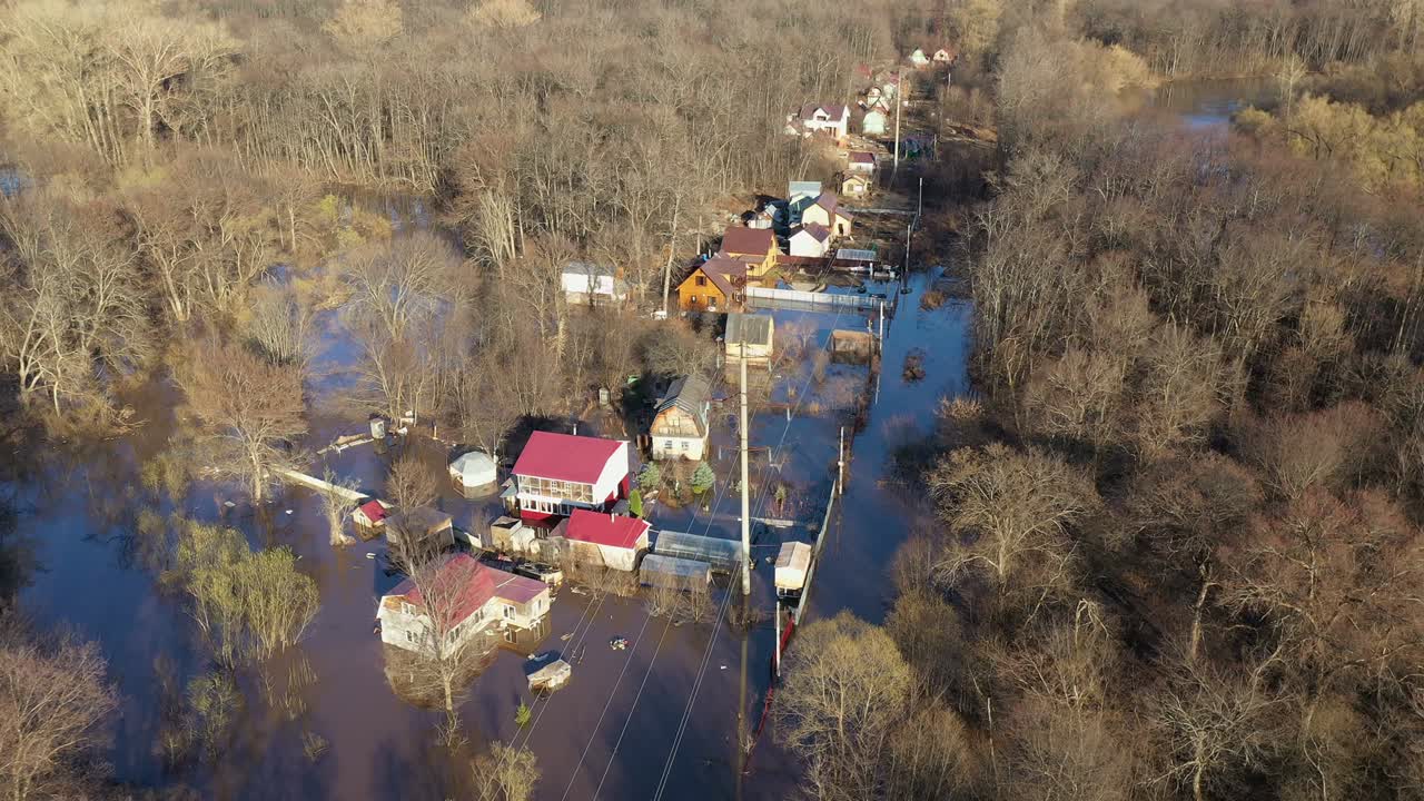 Flooded houses and streets of the microdistrict. Background of the spring woods. Seasonal natural disaster in the village.