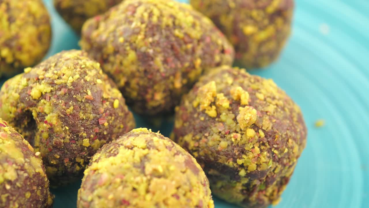 Close-up of pistachio-crusted sweet treats on a blue plate