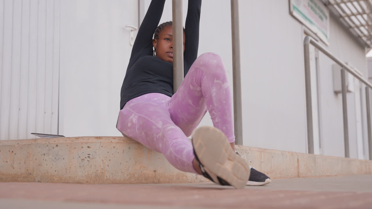 woman pulling on metal railing with determined focus and full body tension, lowangle urban shot showcasing push and pull effort, sneakers planted on ledge, intense workout energy and empowerment