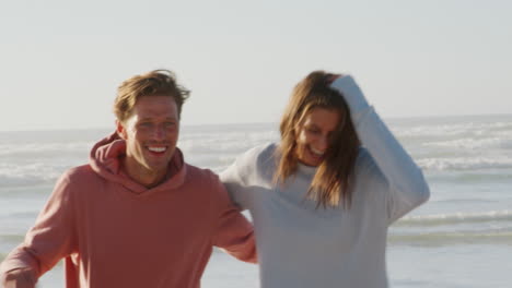 couple having fun running along winter beach together