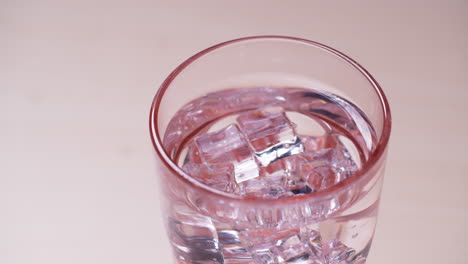 vaso de agua con gas cayendo cubo de hielo