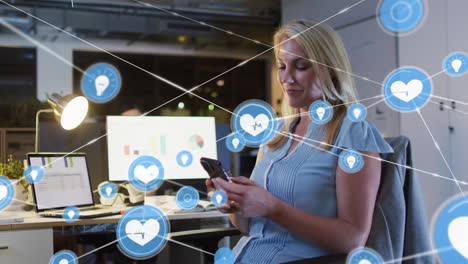 animación de una red de iconos digitales contra una mujer caucásica que usa un teléfono inteligente en la oficina