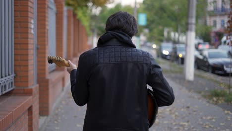 man walking down the street and playing on the guitar