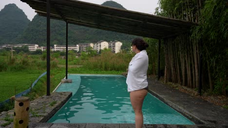 woman dries off beside a pool, overlooking the lush landscape and karst mountains in yangshuo, china