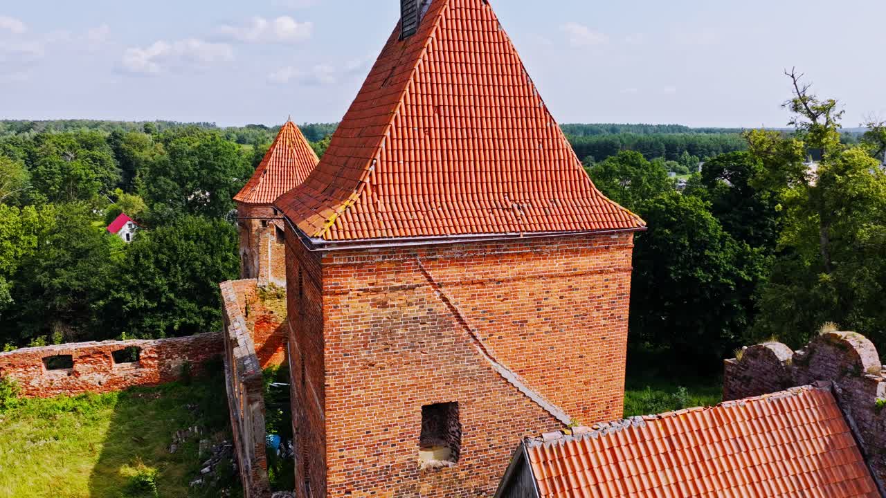Vertical rise, medieval Szymbark fortress roofs above green Polish landscape