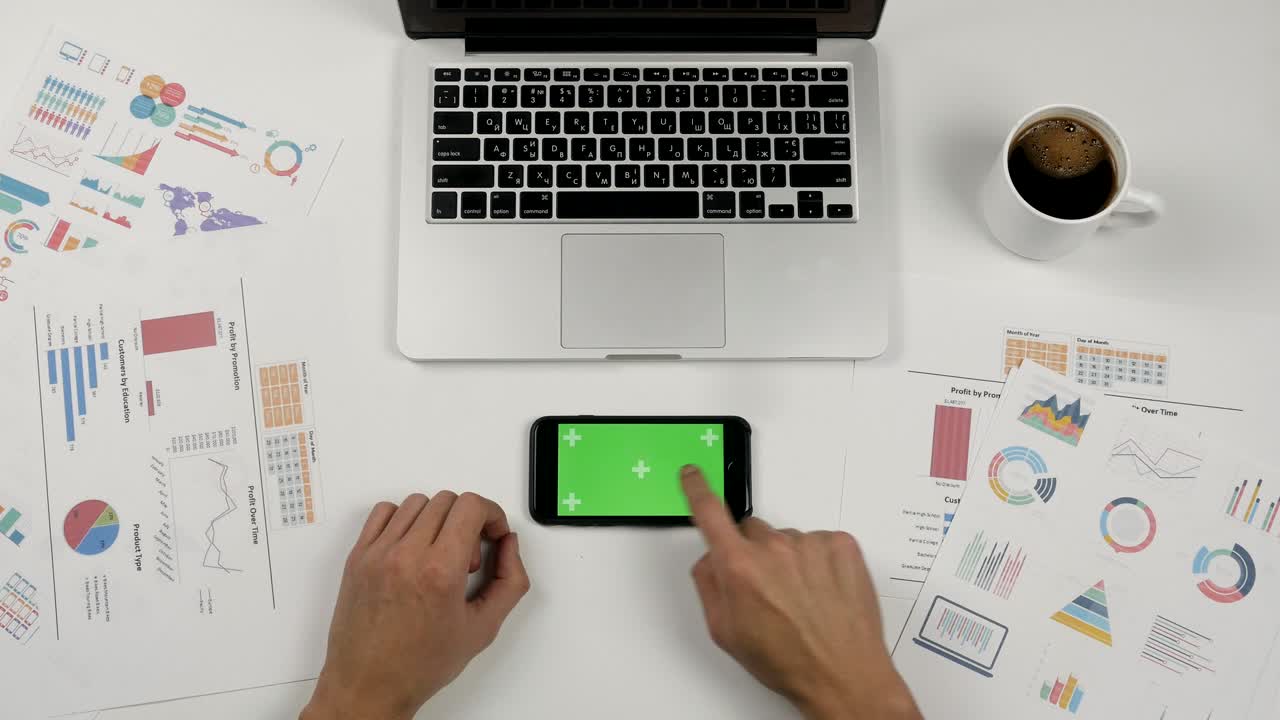 hombre de negocios sosteniendo un teléfono inteligente con pantalla verde en el fondo de la mesa de oficina blanca. manos masculinas desplazando páginas.