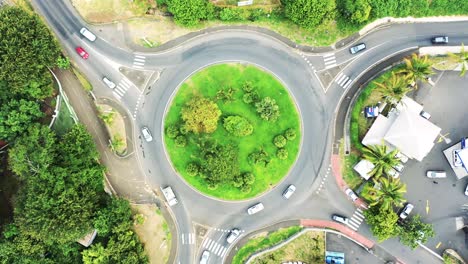 top down aerial zoom in view of a traffic roundabout on a main road in a tropical location