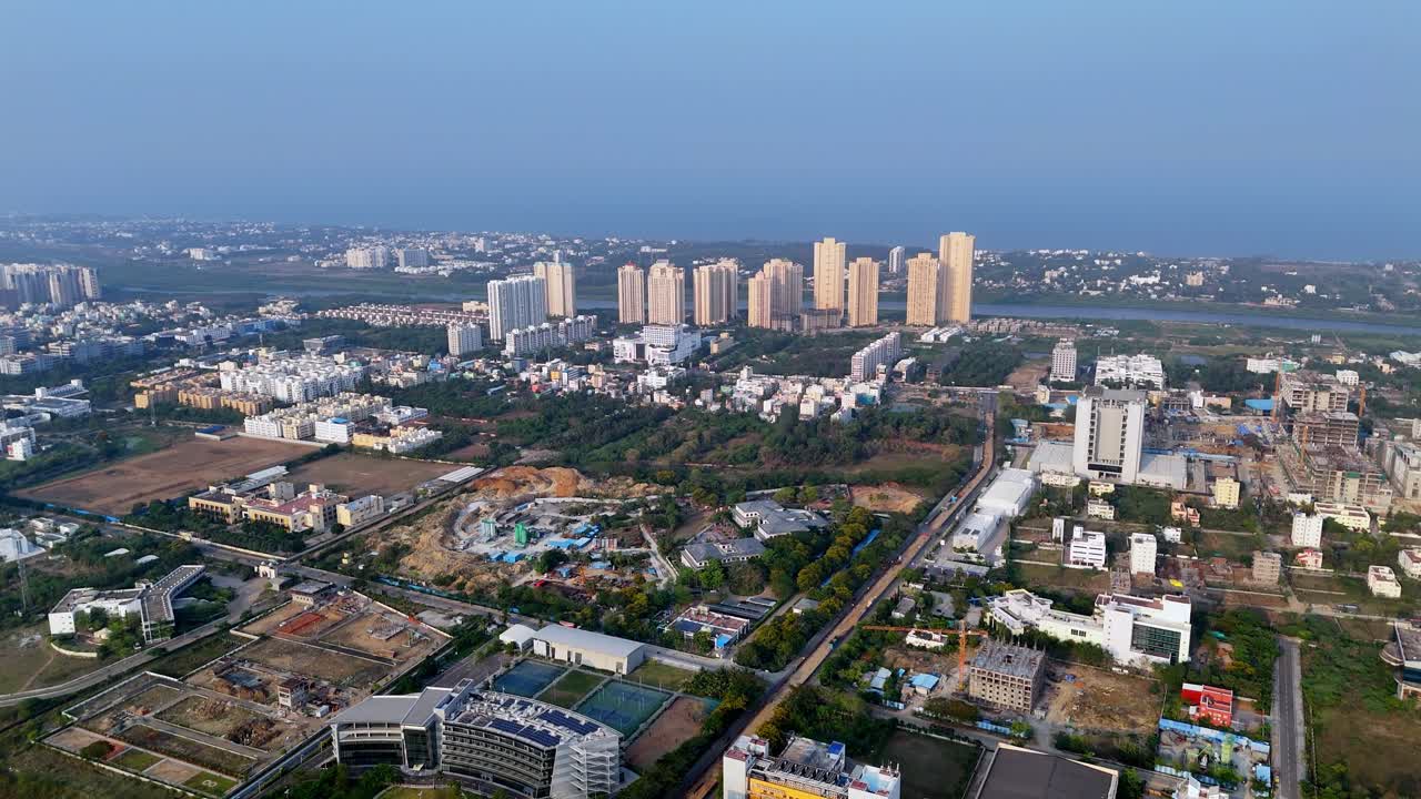 Aerial view of a sprawling urban landscape, characteristic of a rapidly developing metropolitan area, there's a mix of mid-rise buildings, green patches, and construction sites with cranes