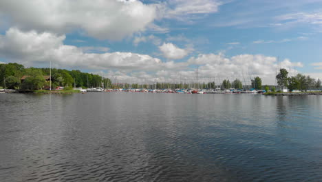 low drone footage parallel with a harbor with sail boats