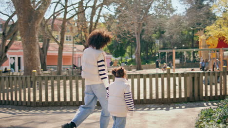 mother daughter going playground at sunny family weekend. happy leisure together