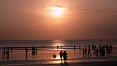 silhouetted people enjoying sunset on tropical beach